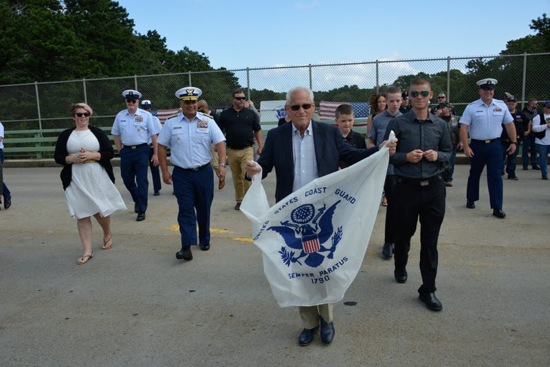 Bradley Finch crosses a Cape Cod bridge holding a Coast Guard Enslgn