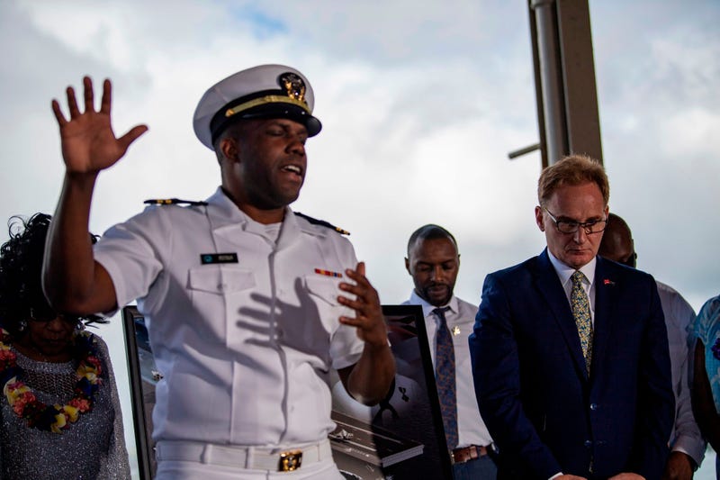 Acting Secretary of the Navy Thomas B. Modly, right, bows his head during an invocation following the unveiling of the new Ford-class aircraft carrier USS Doris Miller (CVN 81)