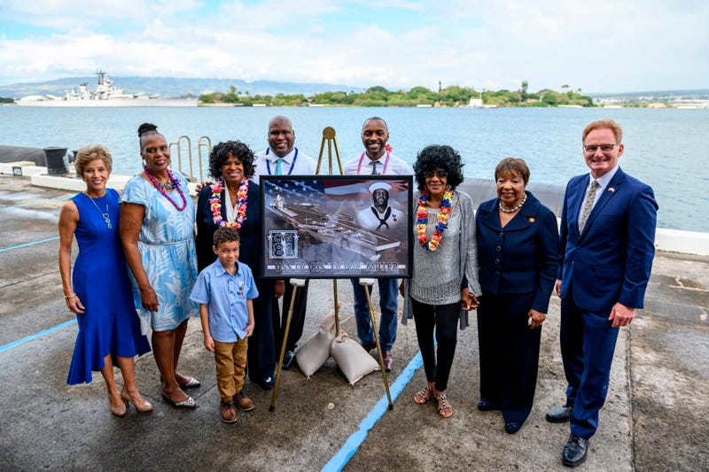 Acting Secretary of the Navy Thomas B. Modly, right, poses for a photo next to a graphic illustration of the new Ford-class aircraft carrier USS Doris Miller (CVN 81) 