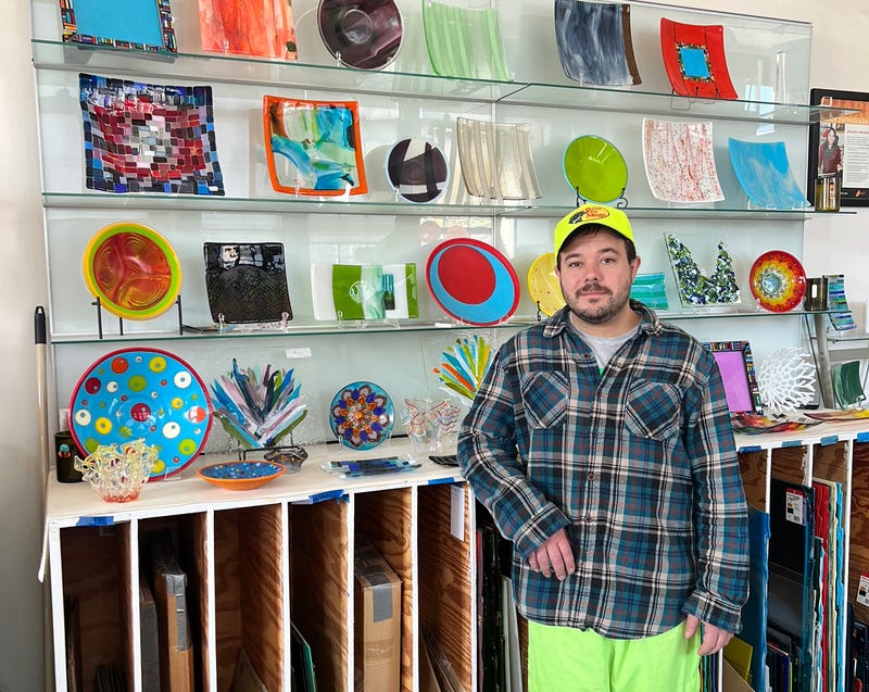 David Nasca stands in front of a display of glass products.