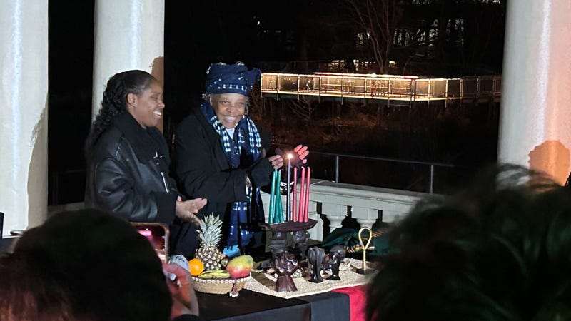 Maisha Sullivan-Ongoza and Milele Sullivan of the Kwanzaa Cooperative light the first candle on the kinara, representing unity.