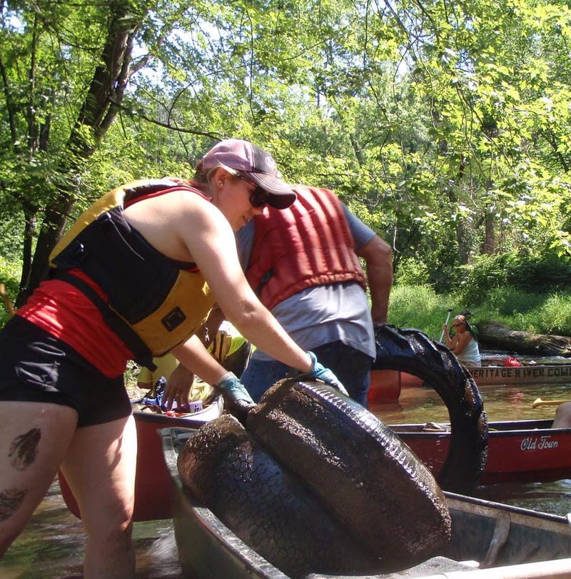 Volunteers picking up tires and other trash in a river