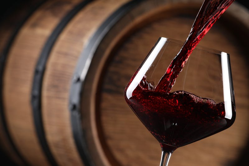 Wine being poured into a glass in front of a barrel