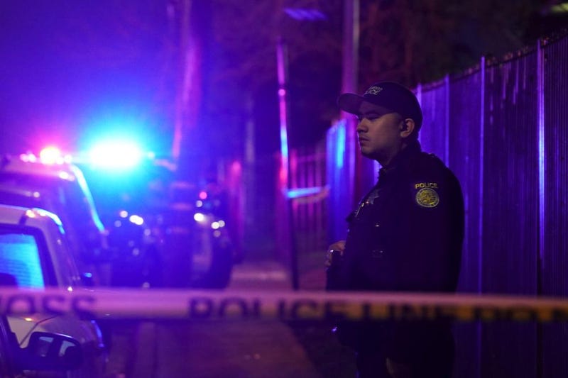 A Sacramento Police officer stands behind police tape blocking the street near the scene of a shooting in Sacramento, Calif., Monday, Feb. 28, 2022. 