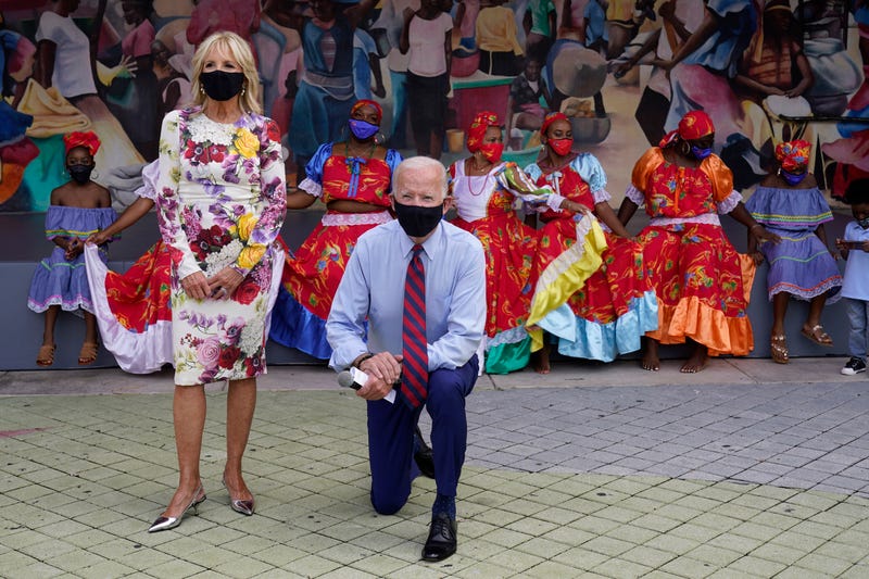 FILE In this Monday, Oct. 5, 2020 file photo, Democratic presidential candidate former Vice President Joe Biden and his wife Jill Biden pose for a photo with dancers as they visit Little Haiti Cultural Complex in Miami. On Friday, Oct. 16, 2020, The Associated Press reported on photos circulating online incorrectly asserting Biden was taking a knee during the national anthem during this campaign event. His campaign confirmed he was kneeling to pose for a picture.