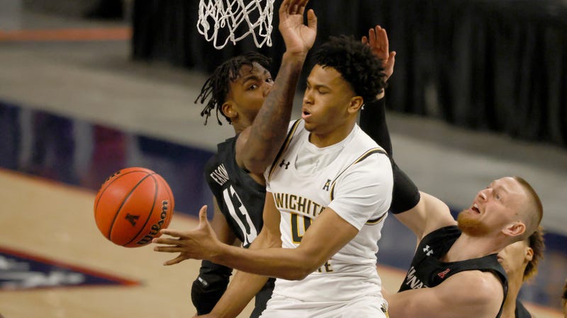Wichita State guard Ricky Council IV, center, tries to pass around Cincinnati forward Tari Eason, left, and Cincinnati guard Mason Madsen, right, during the first half of an NCAA college basketball game in the semifinal round of the American Athletic Conference men’s tournament Saturday, March 13, 2021, in Fort Worth, Texas. (AP Photo/Ron Jenkins)