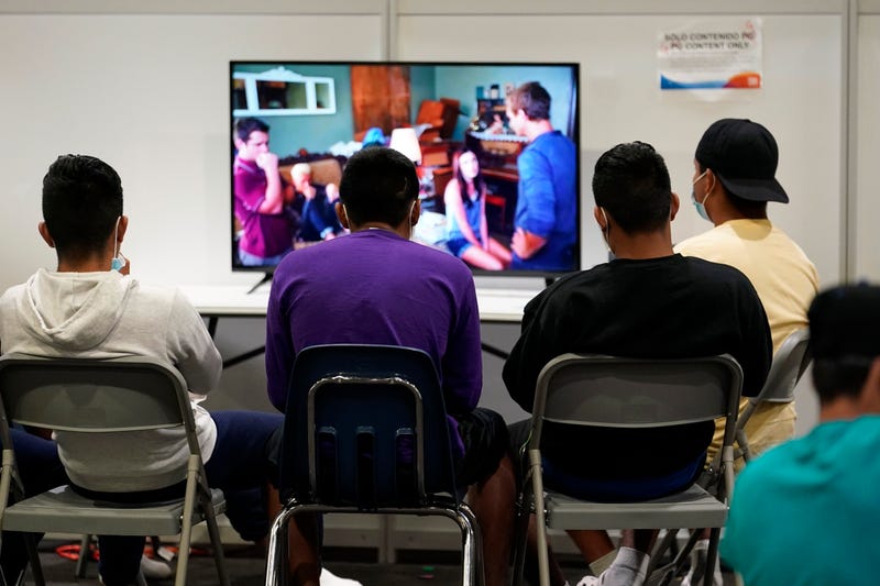 Children watch television at an emergency shelter for migrant children Friday, July 2, 2021, in Pomona, Calif. The Biden administration on Friday gave a rare look inside an emergency shelter it opened to house migrant children crossing the U.S.-Mexico border alone, calling the California facility a model among its large-scale sites, some of which have been plagued by complaints. (AP Photo/Marcio Jose Sanchez, Pool)
