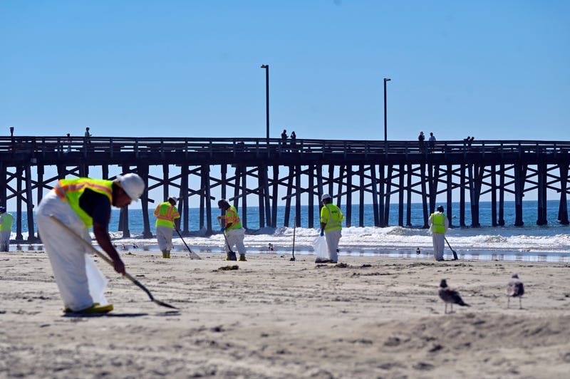 Workers clean oil from the sand