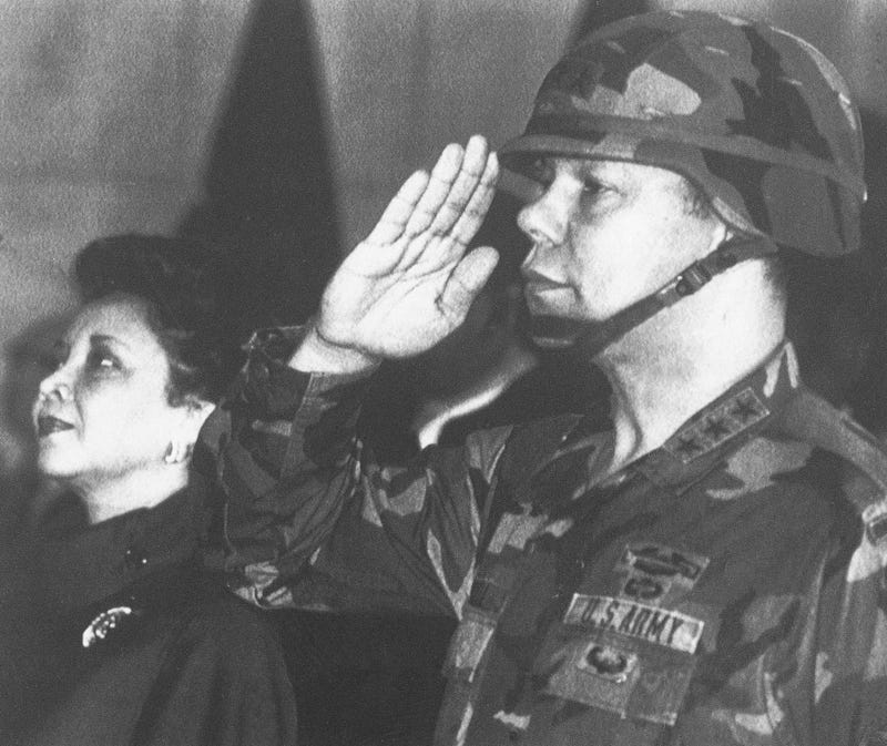In this Dec. 30, 1986, file photo, U.S. Lieutenant General Colin Powell, commander of the 5th U.S. corps, salutes while his wife Alma stands in attention during a farewell ceremony in Frankfurt.