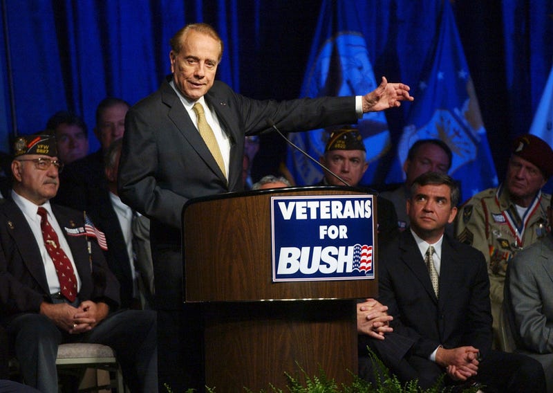 Former U.S. Sen. Bob Dole, surrounded by military veterans, gestures during a Bush-Cheney 2004 National Veterans Leadership Team rally Tuesday afternoon May 11, 2004, in Tampa, Fla.