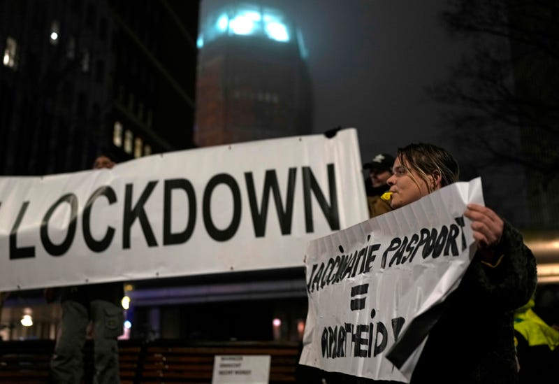 A protestor holds a banner during a small anti-COVID restriction demonstration in the Hague, the Netherlands, Saturday, Dec. 18, 2021.
