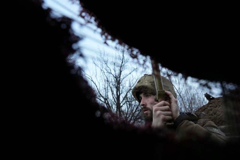 A Ukrainian service member listens to artillery shots standing in a trench on a position at the line of separation between Ukraine-held territory and rebel-held territory near Zolote, Ukraine, late Saturday, Feb. 19, 2022.