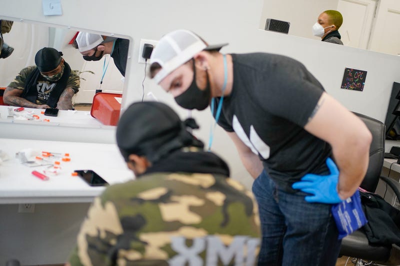 Brian Hackel, right, an overdose prevention specialist, helps Steven Baez, a client suffering addiction, find a vein to inject intravenous drugs at an overdose prevention center, at OnPoint NYC in New York, N.Y., Friday, Feb. 18, 2022