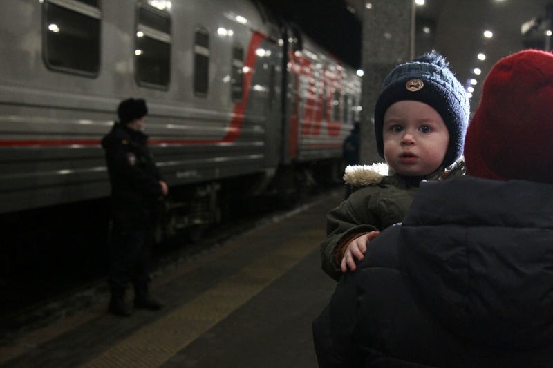 A woman carries a child as they are evacuated from the Donetsk region, the territory controlled by pro-Russia separatist government in eastern Ukraine, as they leave a train to be taken to temporary accommodations, at the railway station in Nizhny Novgorod, Russia, Tuesday, Feb. 22, 2022