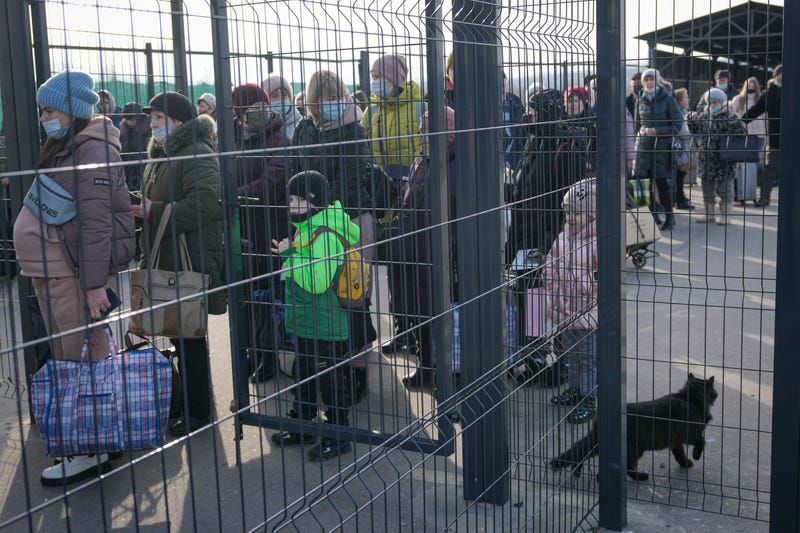 People wait to cross from pro-Russian separatists' controlled territory to Ukrainian government controlled areas in Stanytsia Luhanska, the only crossing point open daily, in the Luhansk region, eastern Ukraine, Tuesday, Feb. 22, 2022