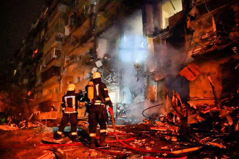 In this handout photo taken from video released by Ukrainian Police Department Press Service released on Friday, Feb. 25, 2022, firefighters inspect the damage at a building following a rocket attack on the city of Kyiv, Ukraine