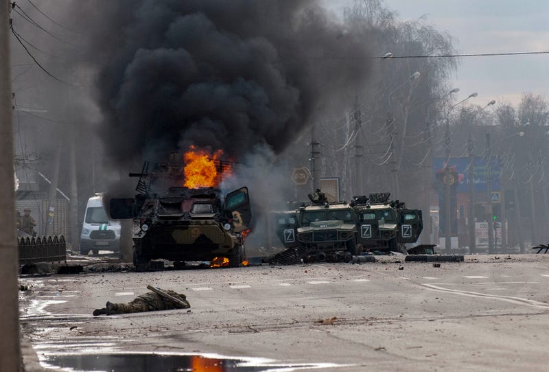 A Russian armored personnel carrier burns amid damaged and abandoned light utility vehicles after fighting in Kharkiv, Ukraine, Sunday, Feb. 27, 2022