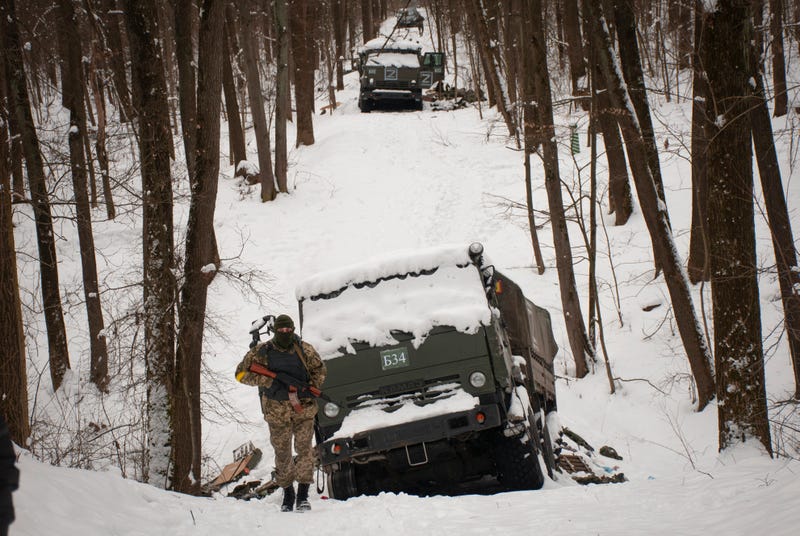 Volunteers of the Ukrainian Territorial Defense Forces inspect a damaged military vehicle in the outskirts of Kharkiv, Ukraine's second-largest city, Monday, March 7, 2022