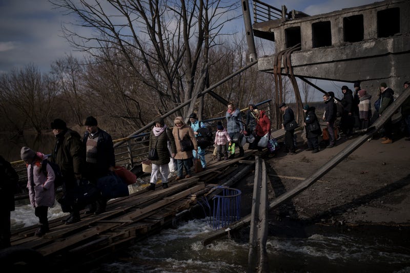 Ukrainians cross an improvised path under a destroyed bridge while fleeing Irpin, on the outskirts of Kyiv, Ukraine, Wednesday, March 9, 2022