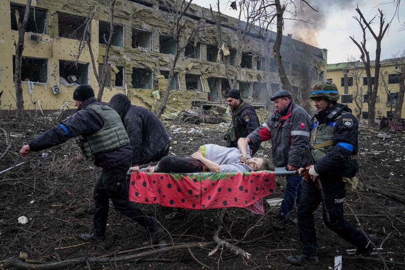 Ukrainian emergency employees and volunteers carry an injured pregnant woman from the damaged by shelling maternity hospital in Mariupol, Ukraine, Wednesday, March 9, 2022