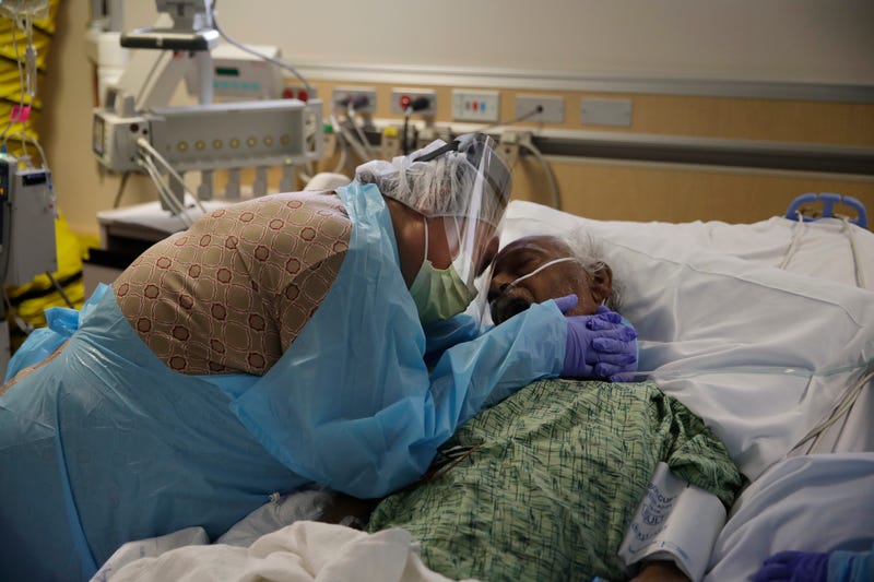 FILE - Romelia Navarro, 64, weeps while hugging her husband, Antonio, in his final moments in a COVID-19 unit at St. Jude Medical Center in Fullerton, Calif., July 31, 2020.