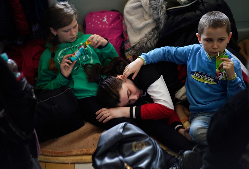A woman and two children, who have fled Ukraine, take rest in the lobby of the train station in Przemysl, Poland.