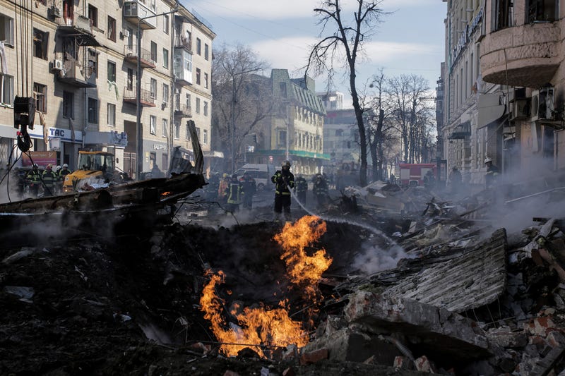 Firefighters extinguish flames outside an apartment house after a Russian rocket attack in Kharkiv, Ukraine's second-largest city, Ukraine, Monday, March 14, 2022