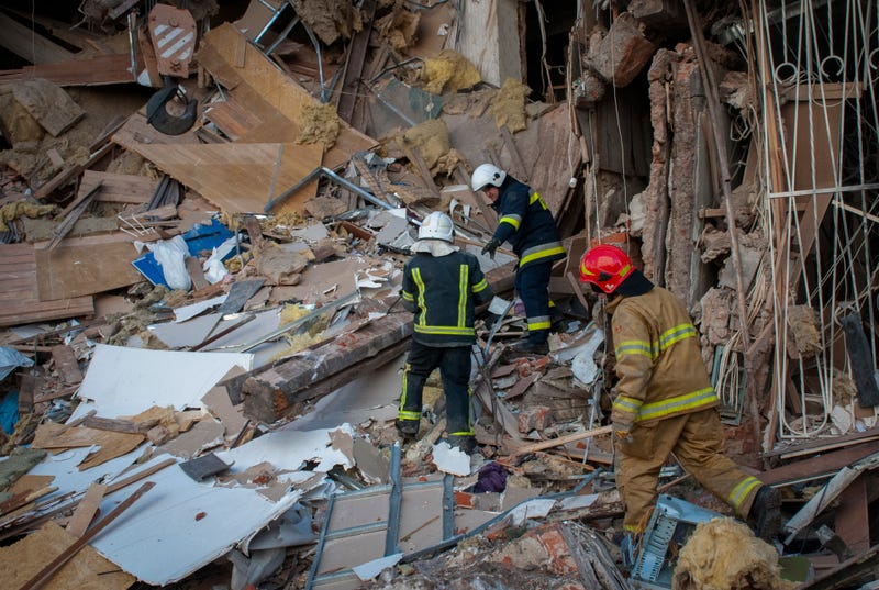 Ukrainian firefighters work by a destroyed apartment building in Kharkiv, Ukraine, Wednesday, March 16, 2022