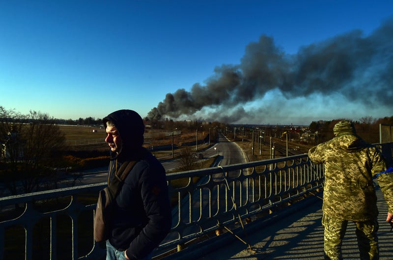 A Ukrainian soldier watches as smoke raises after an explosion near the airport, in Lviv, western Ukraine, Friday, March 18, 2022