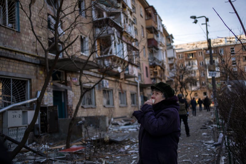 A woman looks at residential buildings damaged by a bomb in Kyiv, Ukraine, Friday, March 18, 2022. Russian forces pressed their assault on Ukrainian cities Friday, with new missile strikes and shelling on the edges of the capital Kyiv and the western city of Lviv, as world leaders pushed for an investigation of the Kremlin's repeated attacks on civilian targets, including schools, hospitals and residential areas.