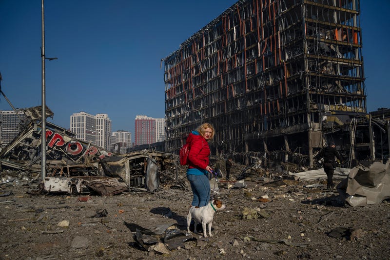 Irina Zubchenko walks with her dog Max amid the destruction caused after shelling of a shopping center, in Kyiv, Ukraine, Monday, March 21, 2022