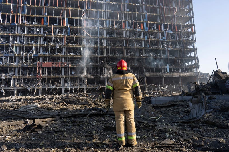 A firefighter looks at the destruction caused after shelling of a shopping center, in Kyiv, Ukraine, Monday, March 21, 2022