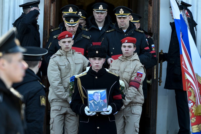 A serviceman carries the photo of Capt. Andrei Paliy, a deputy commander of Russia's Black Sea Fleet, during a farewell ceremony in Sevastopol, Crimea, Wednesday, March 23, 2022. Paliy was killed in action during fighting with Ukrainian forces in the Sea of Azov port of Mariupol