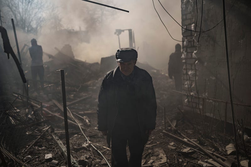 A man walks amid smoke from a burning house, destroyed after a Russian attack in Kharkiv, Ukraine, Thursday, March 24, 2022