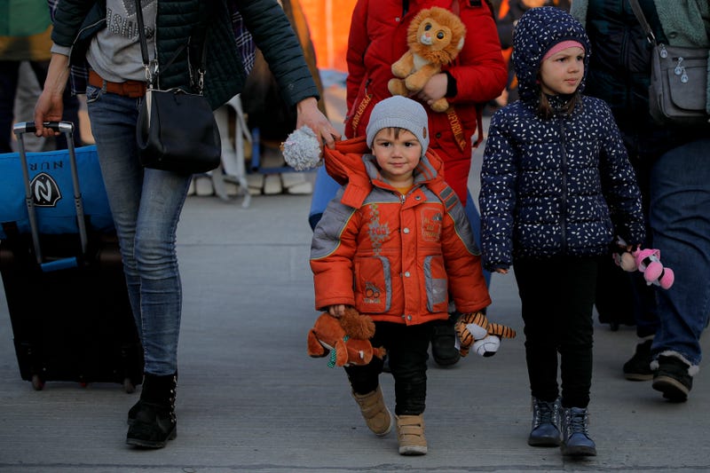FILE - A refugee fleeing the war from neighbouring Ukraine walks with children holding toys after crossing the border by ferry at the Isaccea-Orlivka border crossing in Romania, Thursday, March 24, 2022.