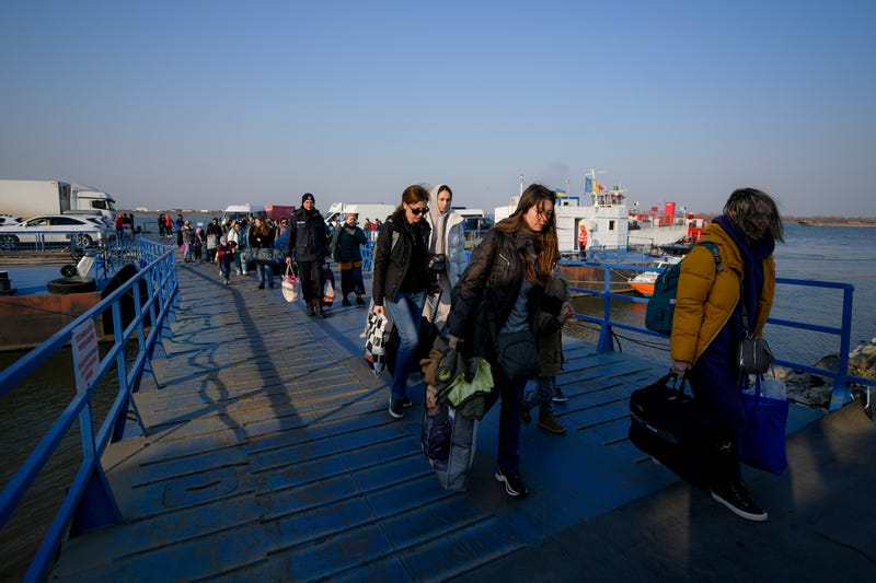 FILE - Refugees fleeing the war from neighbouring Ukraine walk after crossing the border by ferry at the Isaccea-Orlivka border crossing in Romania, Thursday, March 24, 2022.