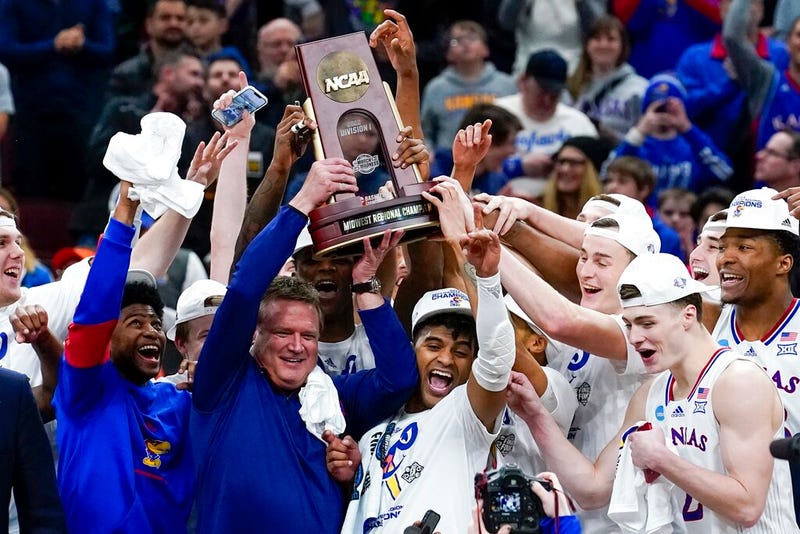 Kansas head coach Bill Self and players hold up the winning trophy after a college basketball game in the Elite 8 round of the NCAA tournament against Miami