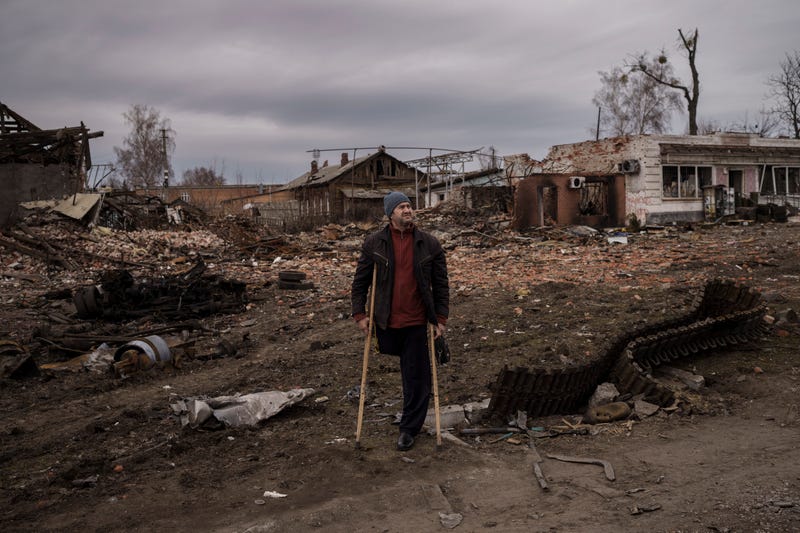 A resident stands next to parts of a destroyed Russian tank in the town of Trostsyanets, Ukraine, Monday, March 28, 2022