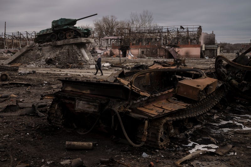 A woman walks past a destroyed tank in the town of Trostsyanets, Ukraine, Monday, March 28, 2022. Trostsyanets was recently retaken by Ukrainian forces after being held by Russians since the early days of the war