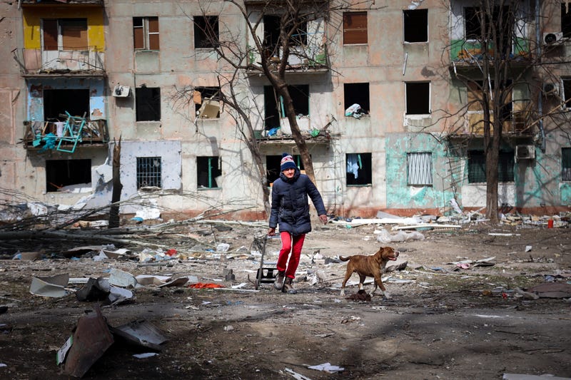 A man walks with his dog near an apartment building damaged by shelling from fighting on the outskirts of Mariupol, Ukraine, in the territory controlled by the breakaway Donetsk People's Republic government, on Tuesday, March 29, 2022