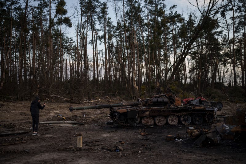 A man takes photos of a destroyed tank near Kyiv, Ukraine, Monday, April 4, 2022