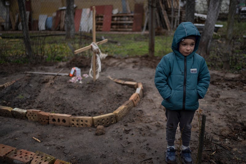 In the courtyard of their house, Vlad Tanyuk, 6, stands near the grave of his mother Ira Tanyuk, who died because of starvation and stress due to the war, on the outskirts of Kyiv, Ukraine, Monday, April 4, 2022