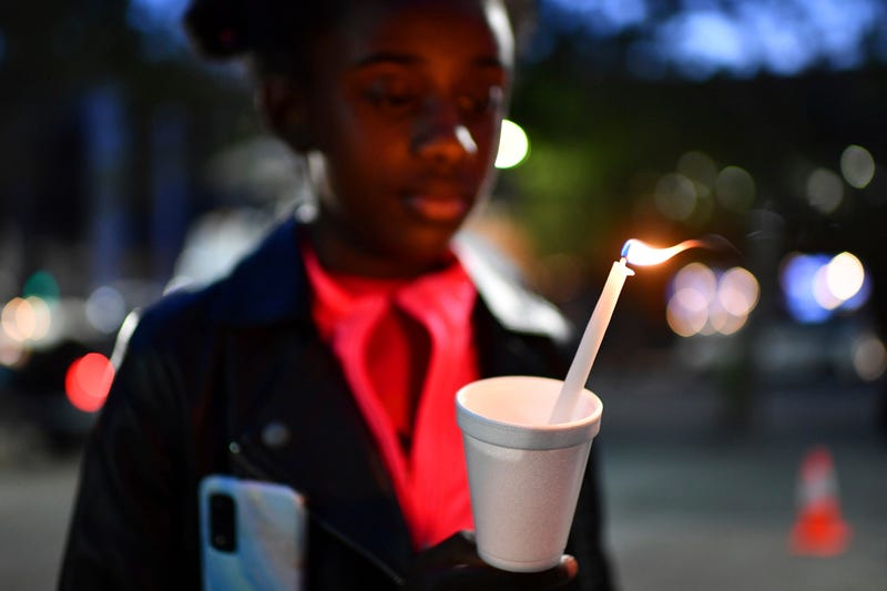FILE - Gabrielle Knox, 9, of Sacramento, stares at the flame of a candle during a vigil held at Ali Youssefi Square in Sacramento, Calif., late Monday, April 4, 2022. Multiple people were killed and injured after a shooting that occurred early Sunday.