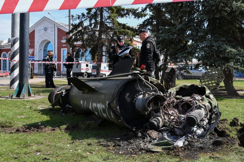 Ukrainian servicemen stand next to a fragment of a Tochka-U missile with a writing in Russian "For children" , on a grass after Russian shelling at the railway station in Kramatorsk, Ukraine, Friday, April 8, 2022