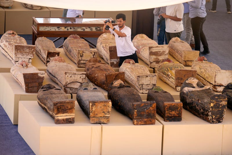 A reporter films painted coffins with well-preserved mummies