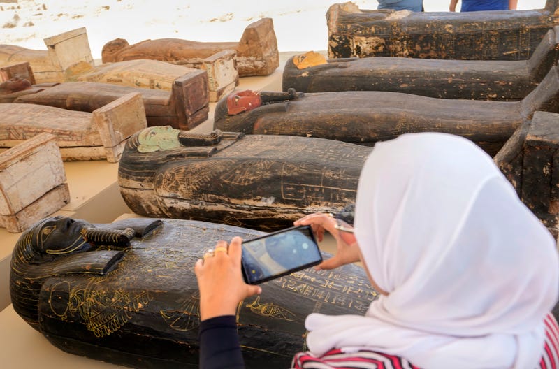 A reporter films painted coffins with well-preserved mummies inside, dating back to the Late Period of ancient Egypt around 500 B.C