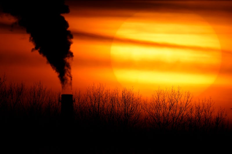 Red sunset with plume of black smoke in front of it