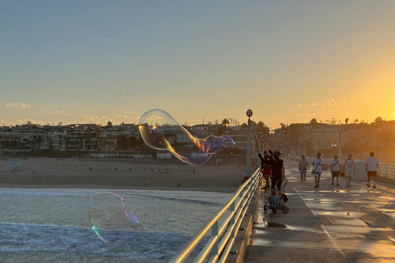 A man creates giant soap suds bubbles at dawn Monday, Sept. 5, on the Manhattan Beach Pier in Manhattan Beach, Calif., as a severe heat wave gripped the state. Most of California's 39 million people are facing sweltering weather.