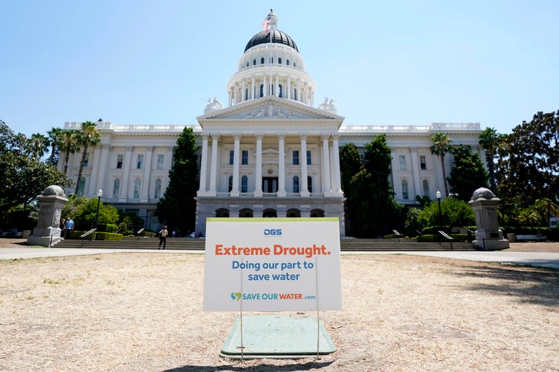 FILE - A sign about saving water is posted on browning grass outside the state Capitol in Sacramento, Calif., on Monday, July 11, 2022. California's water use dropped more than 10% in July compared to two years ago, state officials said Wednesday Sept. 7, 2022.