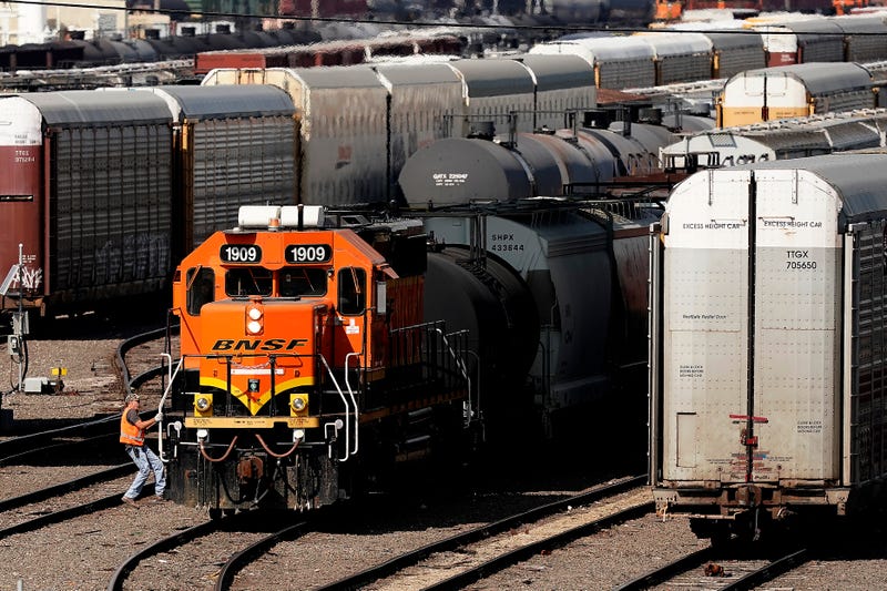 A worker boards a locomotive at a BNSF rail yard.